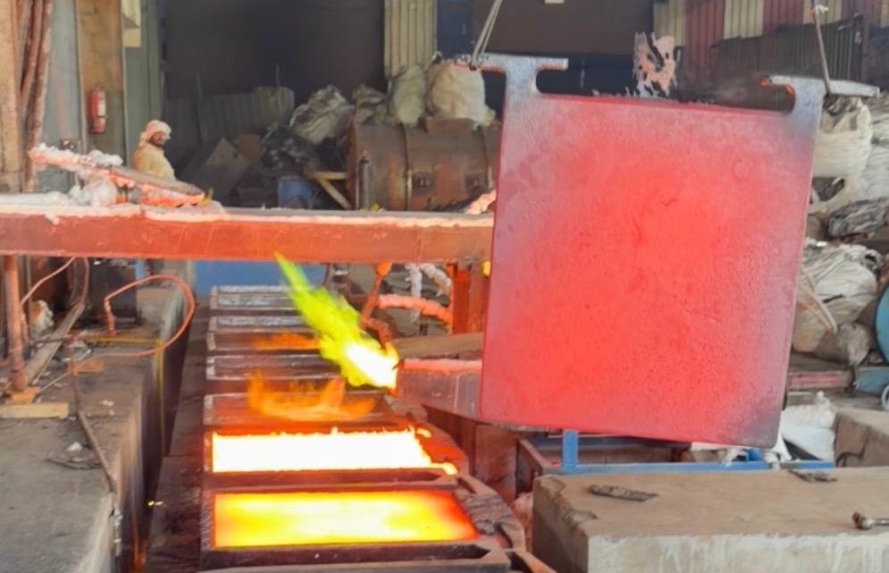 Molten copper glowing in anode moulds beside a freshly cast anode